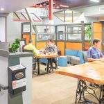 Nowoczesna otwarta przestrzeń coworkingowa z ludźmi pracującymi przy biurkach i laptopach