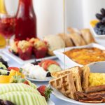 Grupa pracowników biurowych je lunch przy stole z sałatkami kanapkami i napojami