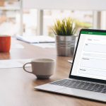 biznesmen przy biurku z laptopem wyświetlającym program do faktur na ekranie